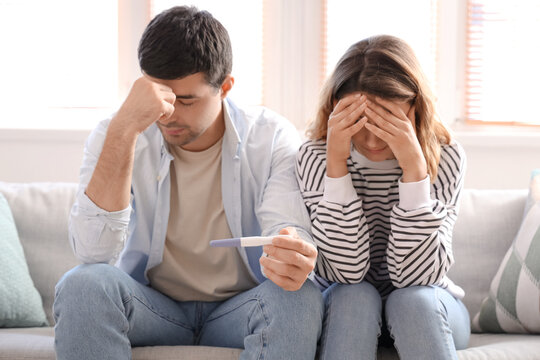 Upset young couple with pregnancy test at home