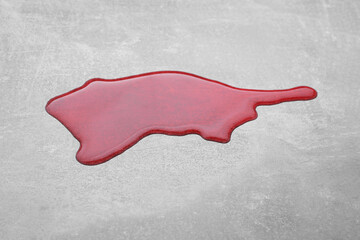 Puddle of red liquid on light grey surface