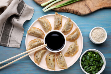 Delicious gyoza (asian dumplings) with green onions and soy sauce served on light blue wooden...