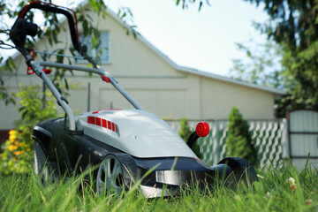 Lawn mower on green grass in garden, space for text