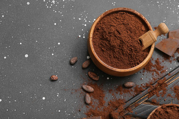 Bowl with cocoa powder and beans on black background