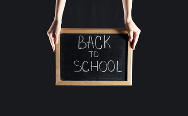 Female hands holding blackboard with text BACK TO SCHOOL on black background
