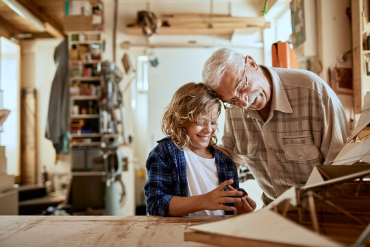Little boy working on a woodworking project with his grandfather in a garage