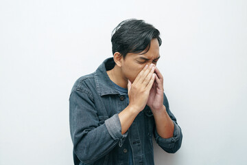 Portrait of Indonesian Asian man sneezing gesture. Unhealthy sick concept isolated white background