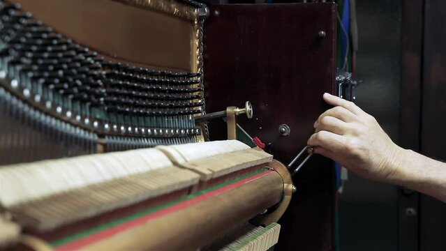 A Man Using a Tuning Fork While Tuning an Old Piano at His Workshop. Close Up. 4K Resolution.