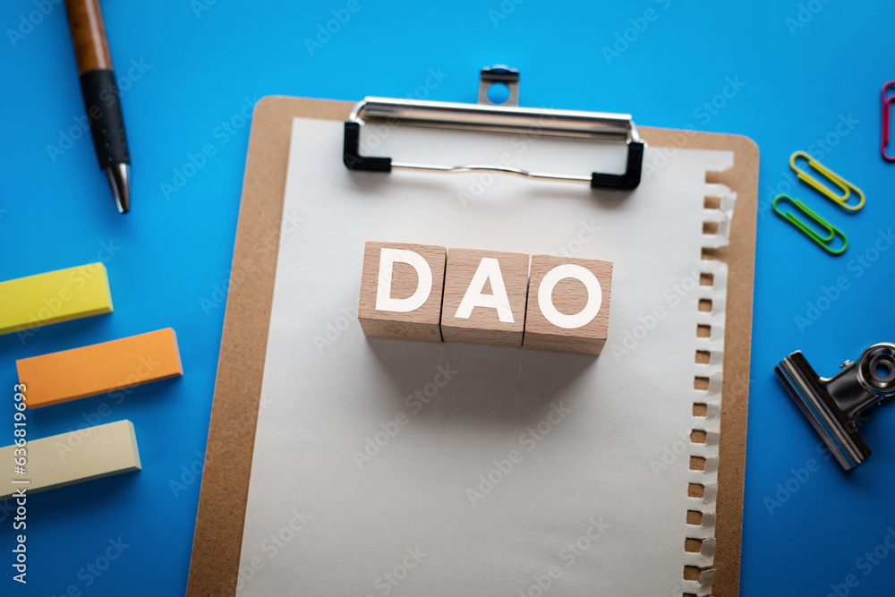 Aufkleber there is wood cube with the word dao. it is an abbreviation for decentralized autonomous organizatio