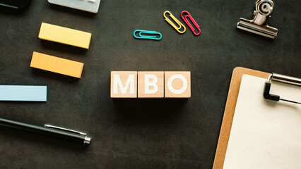 There is wood cube with the word MBO. It is an abbreviation for Management by Objectives as eye-catching image.
