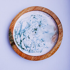 Handmade resin coaster with floral pattern on white background. Selective focus.
