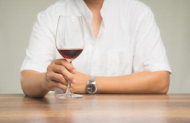 Businessman holding a glass of red wine while sitting at the table.