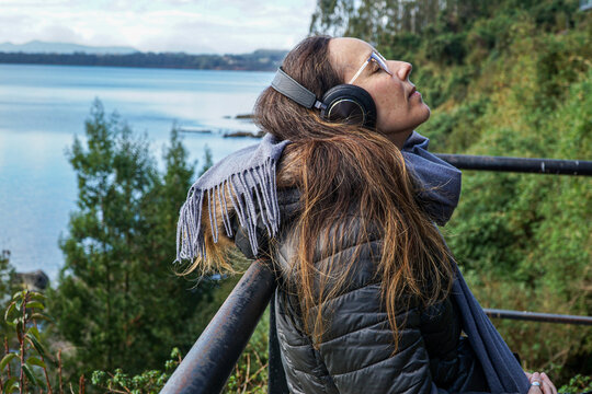 View Of A Woman In A Cold Day Relaxing Outside And Meditating With Headphones.