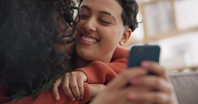 Phone, hug and an lgbt couple laughing together in their home while browsing a social media app. Gay, love and comedy with happy lesbian women looking at memes on a mobile for fun or romantic bonding