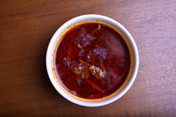 chef signature mala red spicy chilli oil shrimp sambal curry satay peanut paste sauce in bowl for laksa on wood table asian halal food cuisine menu for restaurant