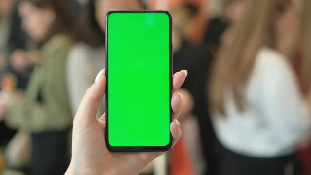 A woman with a smartphone in her hand. Point of View of Woman at Phone with Green Screen for Copy Space. The concept of a successful business woman, feminism. Close-up.