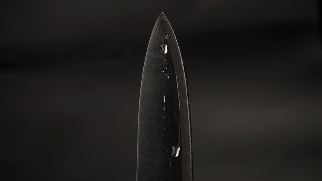 Water drop on sharp knife isolated on dark background. water splashing on knife.