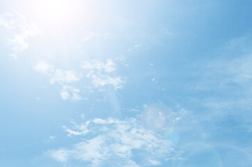 A bright ray of sun against a blue sky with small clouds on a clear day.