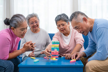 Group of senior people sitting at the table and playing board games together in nursing home