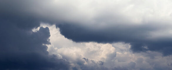 A narrow strip of sky with white clouds is visible through the dark cloud