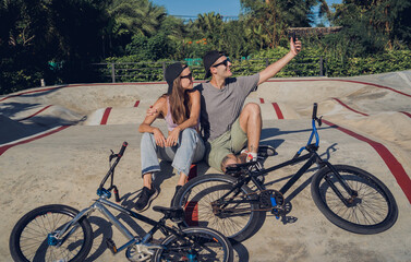 Young happy couple with BMX taking selfie at the skatepark