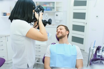 dentist clinic. A female dentist photographing her client's teeth during an appointment at the dental clinic.