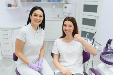Fototapeta premium people, medicine, stomatology and health care concept - happy female dentist with patient girl talking at dental clinic office