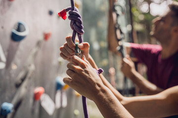 A strong couple of climbers climb an artificial wall with colorful grips and ropes.