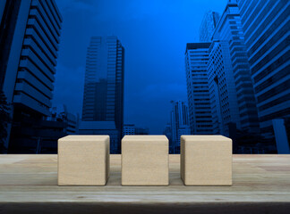 Three block cubes on wooden table over modern office city tower and skyscraper