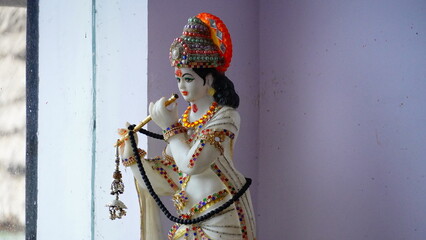 Fototapeta na wymiar a white sculpture of indian god krishna playing flute