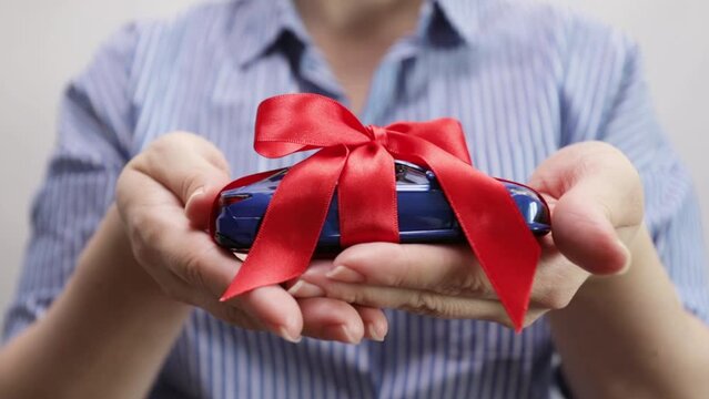 a car a gift for a holiday, a car in a package in female hands, presents in vehicle sales salons, discounts on purchases, additional services of a car dealer