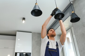 A male electrician changes the light bulbs in the ceiling light. men's household duties. care of...