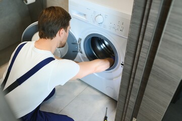 working man plumber repairs a washing machine