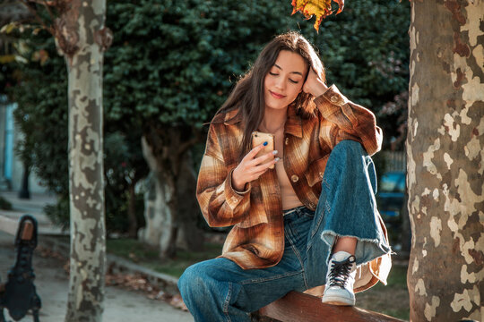 young woman looking at her phone in autumn park