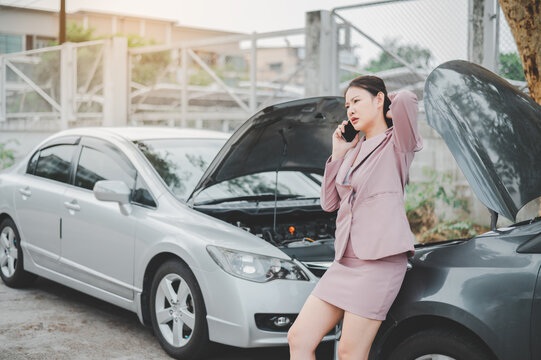 female motorist is calling an insurance or recovery service officer for assistance related to a car accident.