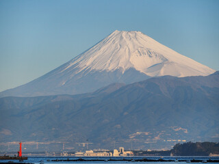 雪に覆われる富士山と赤灯台