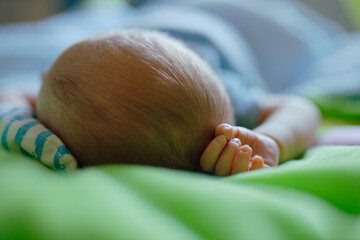 Unrecognizable newborn baby dreaming on the bed