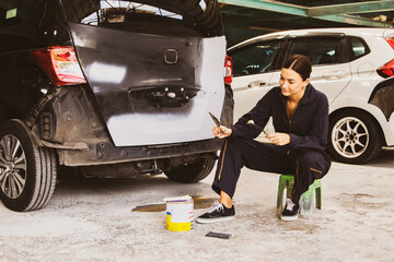 Portrait female car mechanic worker using trowel and putty thicken clean smooth surface as a paint...