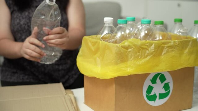 Home recycle eco green zero concept Woman throwing empty plastic bottle in recycling bin with yellow garbage bags at home