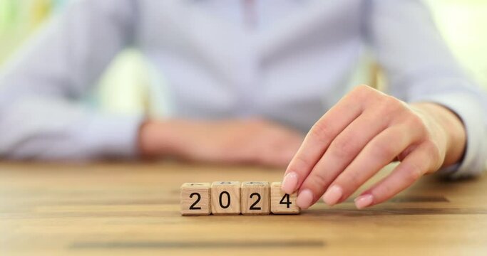 Woman hand puts wooden cube with number 4 to form date as anticipation of starting of new year. Preparation for beginning of new year with new goals slow motion
