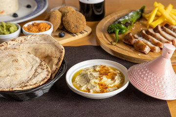 Plastos served at the table ready to taste with hummus, meat and other starters