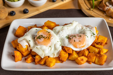 fried eggs presented on a bed of French fries