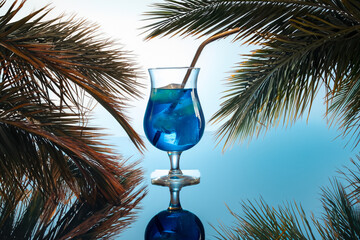 blue coctail on light blue background of beach with palms