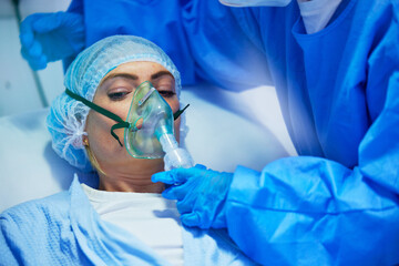 Surgery, anesthesia and doctor with woman with oxygen mask for medical service, operation and...