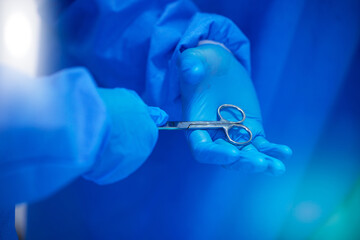 Closeup, surgery and hands with a scissor for healthcare, hospital work and help. Support, team and doctors, surgeons or medical employees with gloves for cardiology or professional cooperation