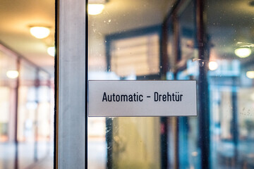 Auf einer automatischen Eingangstür eines Einkaufszentrums steht "Automatic - Drehtür"