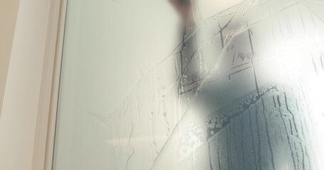 A man pastes a frosted coating on a glass door in a clinic to make the glass door opaque. Applying a matte coating to the glass.