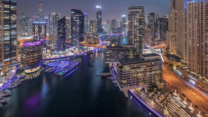 Fototapeta premium Aerial view to Dubai marina skyscrapers around canal with floating boats day to night timelapse