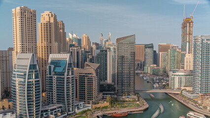 Fototapeta na wymiar Dubai Marina with several boat and yachts parked in harbor and skyscrapers around canal aerial timelapse.