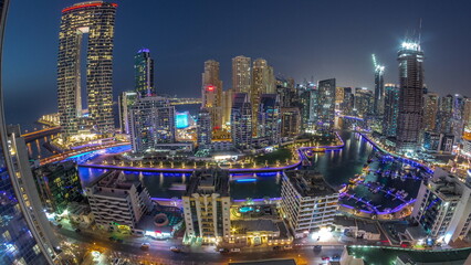 Panoramic view of Dubai Marina with several boat and yachts parked in harbor and skyscrapers around canal aerial day to night timelapse.