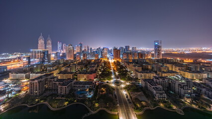 Fototapeta na wymiar Panorama of skyscrapers in Barsha Heights district and low rise buildings in Greens district aerial all night timelapse.