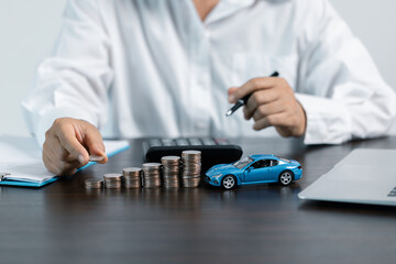 Blue Toy Car In Front Of Businessman Calculating Loan. Saving money for car concept, trade car for...