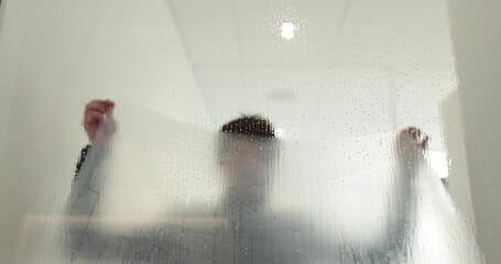 A man pastes a frosted coating on a glass door in a clinic to make the glass door opaque. Applying...